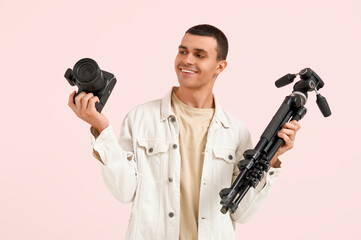 Sticker - Male photographer with modern camera and tripod on pink background