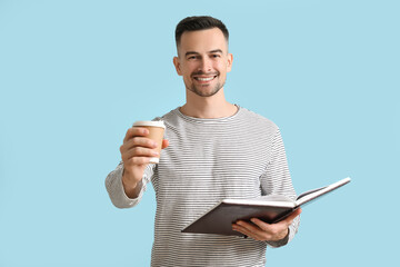 Poster - Happy young man with book and cup of coffee on blue background