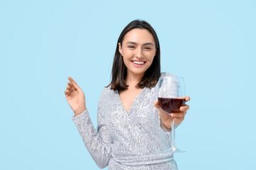 Poster - Beautiful young woman with glass of red wine on blue background