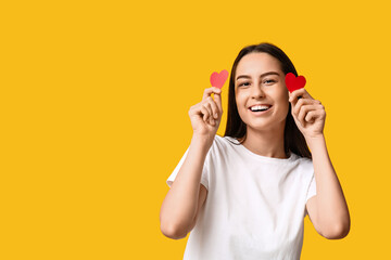 Canvas Print - Beautiful young woman with paper hearts on yellow background