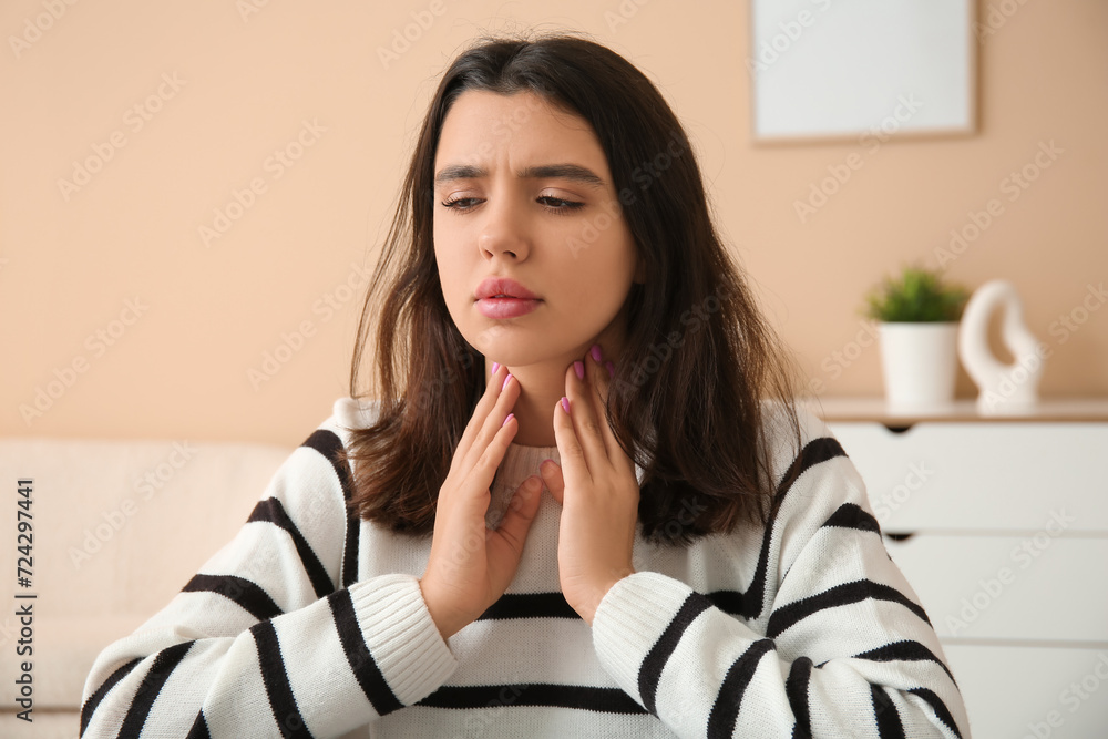Young woman suffering from thyroid gland problem at home