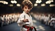 A young boy in a white karate uniform confidently performs a martial arts pose in a dojo full of students.