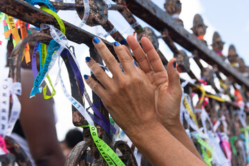 Wall Mural - Tourist hands tying souvenir ribbon on the iron railing of the Senhor do Bonfim church in the city of Salvador, Bahia.