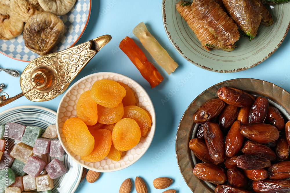 Composition with traditional Eastern sweets and Aladdin lamp for Ramadan on color background
