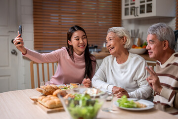 Wall Mural - Asian family doing video call while having lunch in house together. 