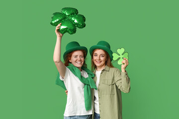 Beautiful women with clovers on green background. St. Patrick's Day celebration