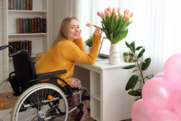 Sticker - Young woman in wheelchair with tulips on table at home. International Women's Day