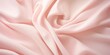 Close-up view of a luxurious soft pink satin fabric with elegant folds and texture.