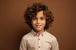 © Iigo - Portrait of a cute little boy with curly hair on brown background