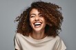 Portrait of a happy young african american woman laughing on gray background