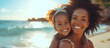 Happy black mother and daughter playing on the beach. Sister gives piggyback ride to little girl by the shore. Lovely child hugs her mom.