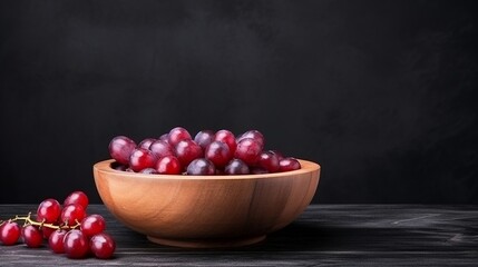 Wall Mural - Red grapes in a wooden bowl on a black background.
