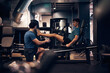 © Flamingo Images - Trainer watching a man do a leg workout in the gym