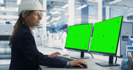 Leinwandbilder - Caucasian Female Technician In Hardhat Working on a Desktop Computer with Green Screen Chromakey Mock Up Display in a Factory Office. Autonomous Technological Research and Development Facility.