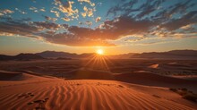 The Sun Is Set Over A Desert With Sand Dunes And Mountains With A Few Clouds In The Sky.