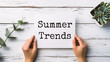 partial view of woman holding white sheet of paper with summer trends