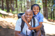 © Tasneem H/peopleimages.com - Happy father, portrait and child hug in forest for family bonding, adventure or outdoor journey in nature. African dad and kid smile in embrace for fresh air, trip or holiday break outside in woods