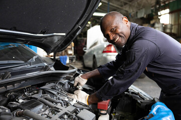 African mechanic worker checking and fixing a car in garage