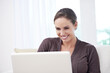 © Katie/peopleimages.com - Woman, smile and laptop on sofa for remote work, update blog post or reading news on social media at home. Happy freelancer, computer and download with internet and movie subscription in living room