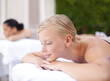 © Elliott/peopleimages.com - Spa, woman and relax on massage bed with smile for wellness, zen and beauty treatment for body care. Person, sleeping and physical therapy at resort, salon table and luxury on holiday or vacation