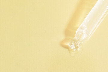 Canvas Print - Top view of pipette dropper with shining transparent liquid on beige background with hard shadow. Copy space