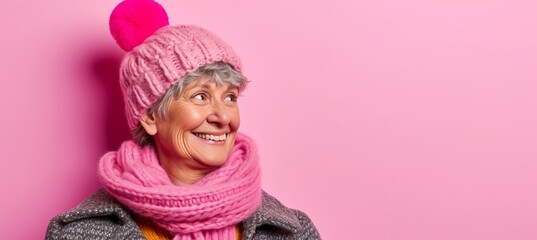 Wall Mural - Cheerful elder woman in hat and scarf, isolated on pastel background with copy space