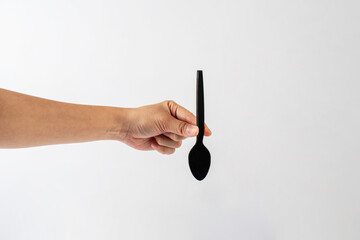 Wall Mural - Black plastic spoon in hand on white background