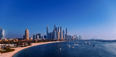 Wall Mural - Aerial view skyscraper of Dubai Marina sand beaches with sea in Persian gulf, sunset. Banner UAE tourism, sunny day
