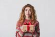 © youriy - Woman holding a gift box with a red bow looking uncertain