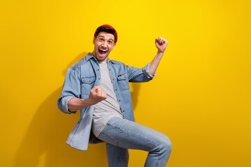 Poster - Photo of charming excited guy wear denim jacket rising fists yelling yeah empty space isolated yellow color background