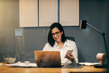 Wall Mural - View through the glass of a businesswoman sitting at office using cutting edge technologies.