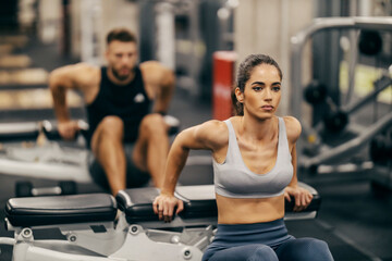 Wall Mural - Portrait of a sportswoman doing bench dip in a gym.