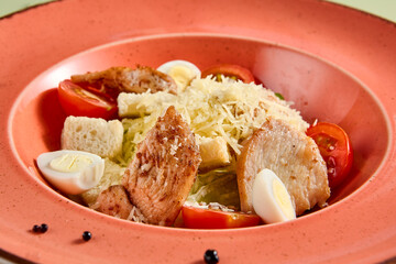 Canvas Print - Elegant Caesar salad with grilled chicken on a coral plate, a refreshing choice for a healthy meal