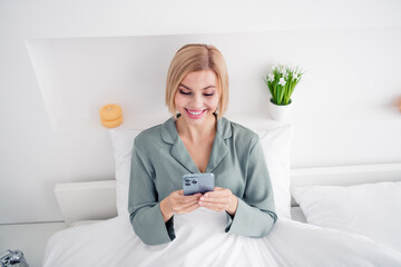 Poster - Photo portrait of pretty blonde young girl sit bed hold telephone eshopping wear trendy gray nightwear bright bedroom interior design