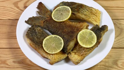 Wall Mural - Fried carp pieces with lemon on dish on rustic table