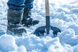 Person wearing winter attire clearing snow from driveway with large shovel on cold winter day