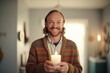 man in sweater offering a candle set towards camera with a grin