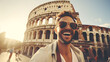 Portrait of a happy young man in sunglasses standing in front of Colosseum in Rome, Italy