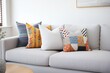 a variety of patterned cushions arranged on a modern grey couch