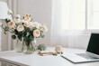 Ranunculus and eucalyptus flowers, with a laptop screen on a white table. office at home for women. White wall and minimalist floral desktop