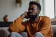 © Jorge Ferreiro - thoughtful african man sitting on the sofa at home