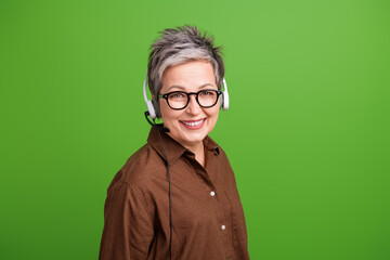 Poster - Photo of pleasant cheerful woman with short hairstyle wear brown shirt in headset consultating clients isolated on green color background