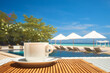 Coffee cup on a table in a restaurant on the beach against the backdrop of a swimming pool and beach umbrellas on a summer day. Focus on the table with a coffee cup.