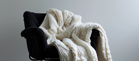 Wall Mural - A black chair draped with a hand-knitted white wool blanket.