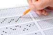 © uwimages - Student filling out answers to a test with orange pencil close-up