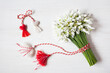 Bouquet of snowdrops flowers, red and white rope with tassels martenitsa, hearts on a wooden background. Postcard for the holiday of March 1
