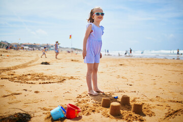 Wall Mural - Adorable preschooler girl playing on the sand beach at Atlantic coast of Brittany, France