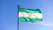 Flag of Andalusia waving in blue sky. Andalusian banner, Spanish federal state
