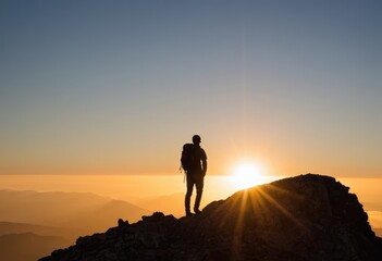 Wall Mural - A lone explorer’s silhouette on a mountain peak, capturing the spirit of adventure