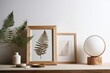 A round candle holder, a dried fern leaf in a frame, a blank picture in a white frame, and a fern leaf on a wooden table with a light background. Scandinavian design It is applicable as a layout